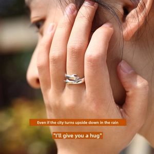 Detailed view of silver hugging hands ring featuring an adjustable open band design