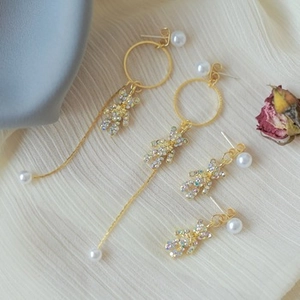 Detailed view of asymmetric bear earrings with pearls and rhinestones on soft fabric