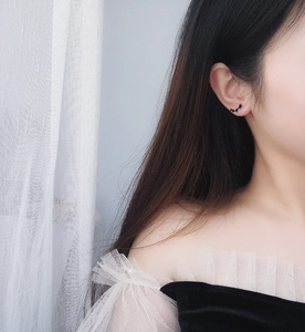 Close-up of a black bat-shaped stud earring worn on a female ear for a gothic style