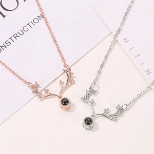 Detailed view of rose gold and silver antler necklaces with projection stones on a card