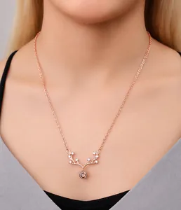 Close-up of rose gold reindeer antler necklace with zircon stones worn by a model