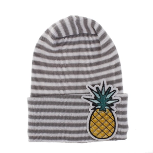 Detail of baby knit hat featuring grey and white stripes with yellow pineapple embroidery