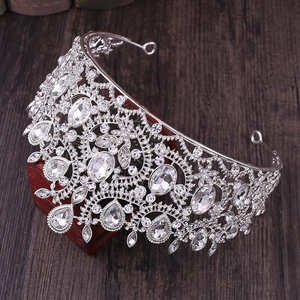 Detailed side view of silver Baroque crown with crystals on red wooden block
