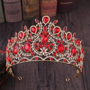 Detail of a baroque gold tiara with large red crystals on vintage books and wood