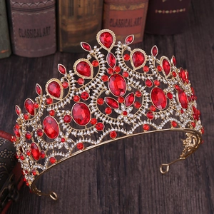 Close-up of golden baroque crown featuring large red gemstones and sparkling crystals