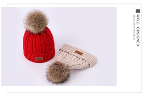 Close-up of cable knit texture and faux fur pom-poms on red and beige winter beanies