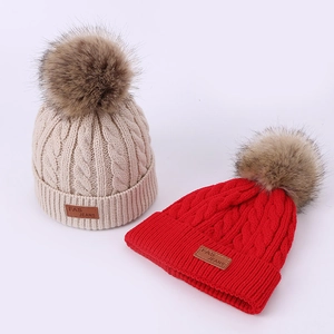 Kids cable knit winter beanie with double fluffy pom poms and leather patch detail