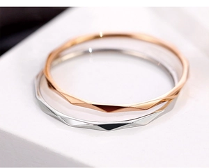 Close-up of geometric faceted V-shape stackable rings in rose gold and silver steel