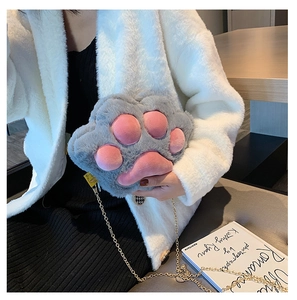 Gray plush cat paw bag with pink pads and gold chain strap worn by model