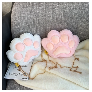 Detail of plush cat paw bags with pink pads and gold chain straps on soft fabric