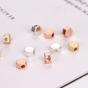 Macro detail of hexagonal metal spacer beads in gold, silver and rose gold finishes