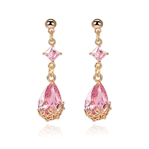 Close-up of 18K gold earrings with pink teardrop crystal and hollow floral base