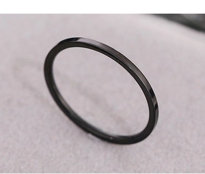 Macro shot of a minimalist black thin ring with polished surface on soft fabric background