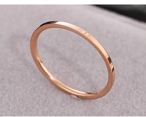 Macro shot of minimalist rose gold stainless steel thin band ring on beige velvet