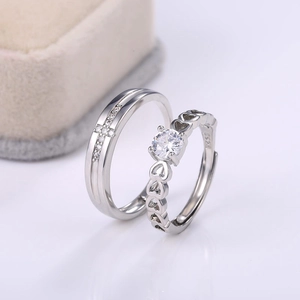 Close-up of silver couple rings with heart-shaped design and sparkling zircon stones