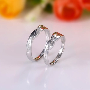Macro shot of silver couple rings with promise engraving and inlaid zircon detail