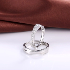 Macro detail of silver intertwined wave rings with sparkling cubic zirconia on white surface