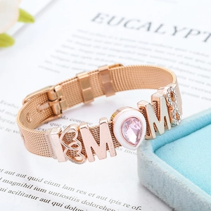 Macro detail of rose gold mesh bracelet featuring MOM charm with pink crystal and heart