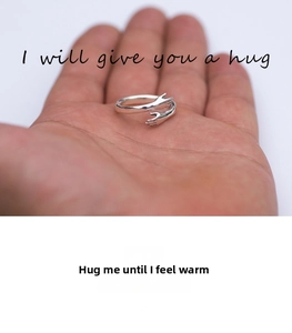 Detail of silver hugging hands ring on palm featuring unique creative embrace design