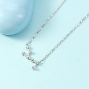 Minimalist silver constellation necklace with shimmering crystals on a light blue background