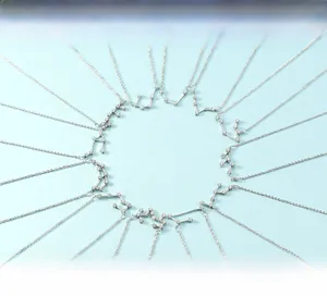Macro shot of silver zodiac constellation necklaces with zircon stones on blue background