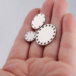 Polished stainless steel round pendant discs in three sizes held in hand for DIY jewelry
