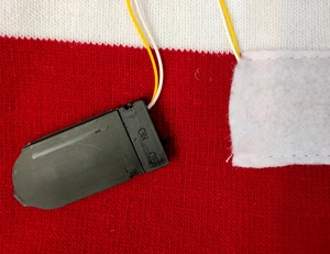 Detail shot of the LED light battery box with ON/OFF switch on the knitted Christmas hat