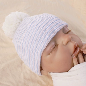 Close-up of baby striped knit hat with a large white fluffy pompom on the top