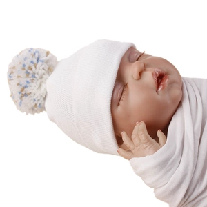 Close-up detail of white double-layer knitted newborn hat featuring a colorful pom-pom