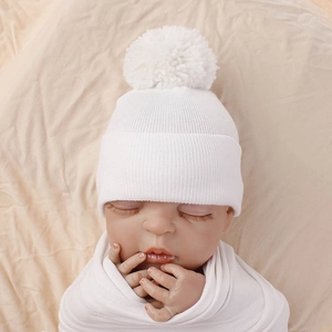 Close-up detail of a white thickened newborn knit beanie with a fluffy pom pom.