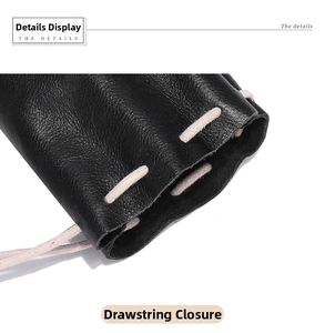 Detail of black pebbled leather texture and beige drawstring closure on the pouch