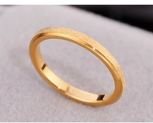 Detail of matte frosted gold ring with polished edges on soft grey textured fabric