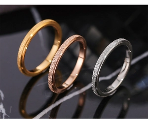 Macro detail of three matte frosted stainless steel rings in gold, rose gold and silver