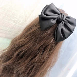 Elegant large black satin multi-layer bow hair clip shown on long wavy hair back view
