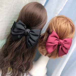 Detail of burgundy and black satin bow hair clips on models with elegant velvet texture
