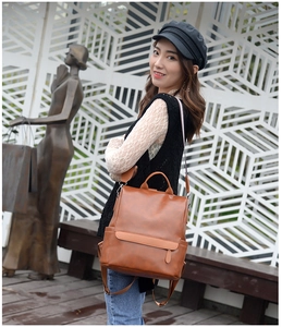 Brown vintage faux leather backpack on female model featuring adjustable straps and pockets