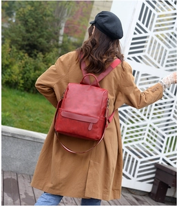 Detail of red leather backpack straps and side pocket shown on female model back