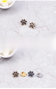 Detail view of cute cat paw earrings with black and white rhinestones in gold and silver