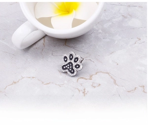 Macro detail of cute cat paw stud earring with black and white crystals on marble