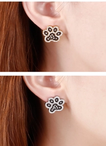 Close-up of a model wearing cute gold and silver paw-shaped stud earrings with crystals