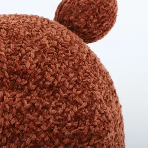 Macro detail of dark brown chenille knit fabric and rounded bear ear on winter baby hat