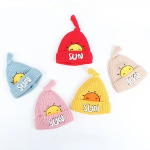 Close-up of five colorful knitted baby hats with sun embroidery and top knot detail