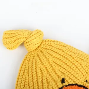 Close-up of yellow knit baby hat with knotted top and cute duck embroidery detail