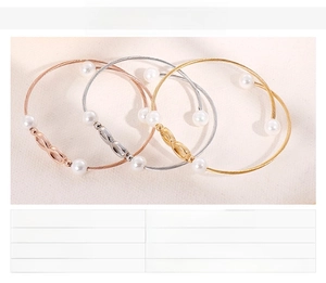 Detail van drie gedraaide roestvrijstalen armbanden met infinity-symbool en schelpparels