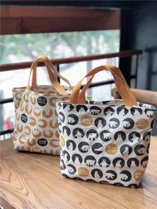 Détail de sacs à lunch en toile avec motifs d'ours polaires et poignées jaunes sur bois