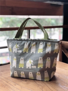 Détail du sac à déjeuner en toile grise avec motifs d'ours polaires et anses vertes