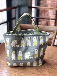 Détail du sac à lunch en coton isolé avec imprimé ours polaire et poignées vertes sur bois
