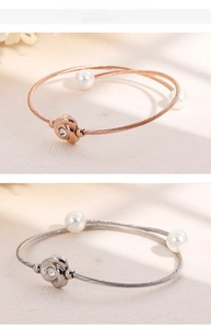 Détail de bracelets torsadés en acier inoxydable avec motif rose et perles blanches