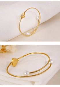 Détail du bracelet perles doré avec pendentif rose sur textile en lin blanc