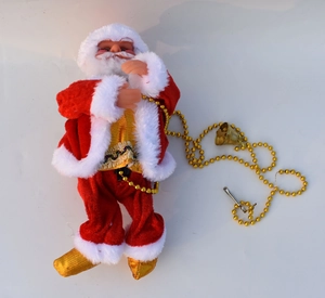 Detailed view of Santa Claus figurine with red suit, golden boots, and festive beads